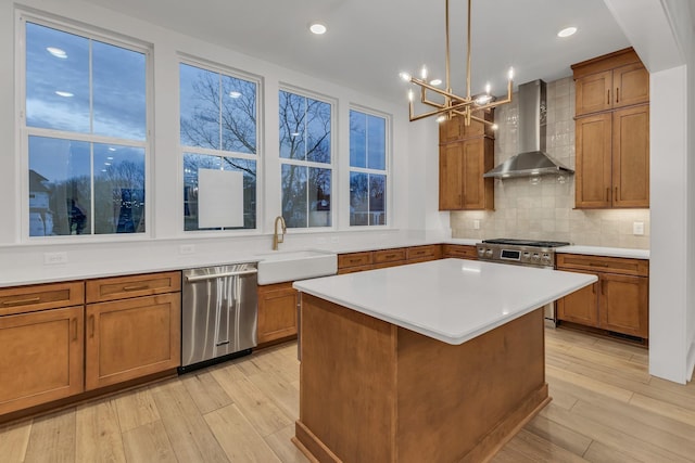 kitchen with wall chimney exhaust hood, a center island, light hardwood / wood-style flooring, appliances with stainless steel finishes, and decorative backsplash