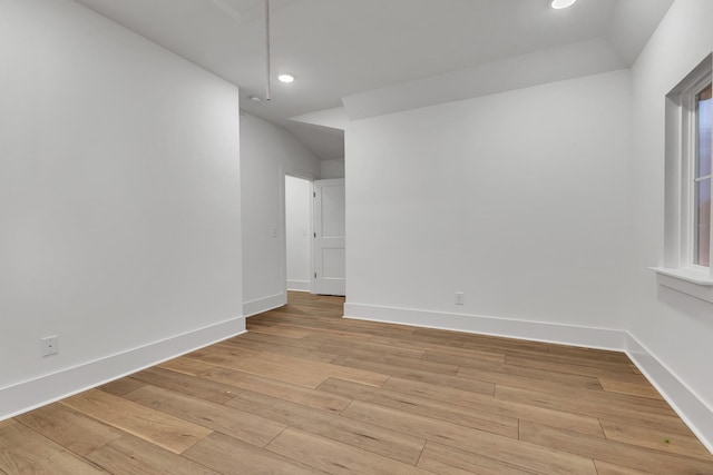 spare room featuring vaulted ceiling and light wood-type flooring