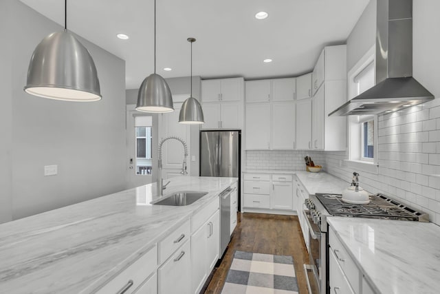 kitchen featuring white cabinetry, sink, stainless steel appliances, light stone countertops, and wall chimney range hood