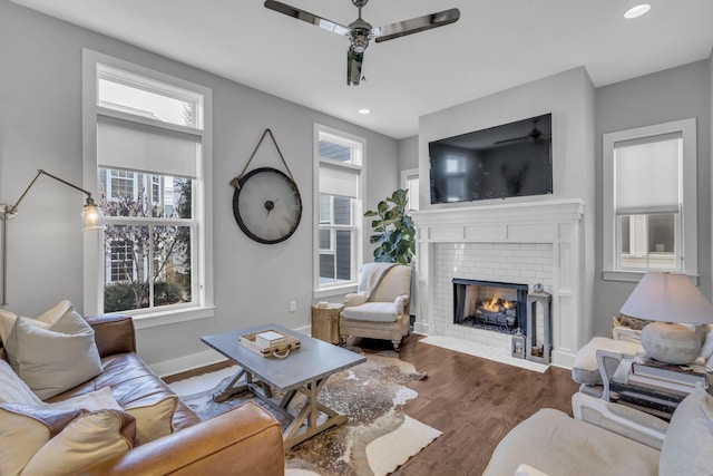 living room with hardwood / wood-style flooring, ceiling fan, and a fireplace