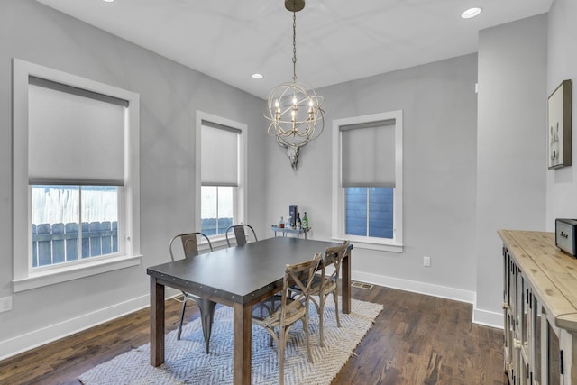 dining area with dark wood-type flooring, a wealth of natural light, and a chandelier