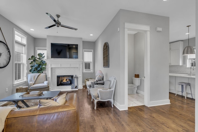 living room with ceiling fan, sink, hardwood / wood-style floors, and a fireplace