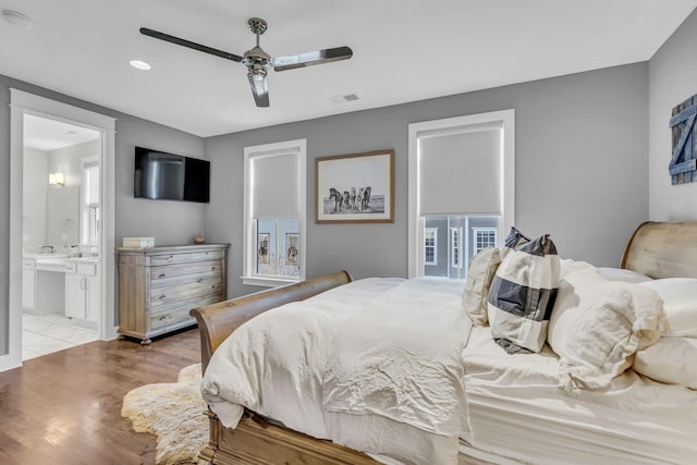 bedroom with ceiling fan, ensuite bath, and light hardwood / wood-style flooring