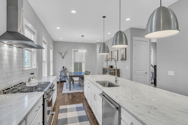 kitchen with stainless steel appliances, white cabinetry, pendant lighting, and wall chimney exhaust hood