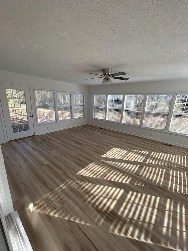 unfurnished sunroom with ceiling fan