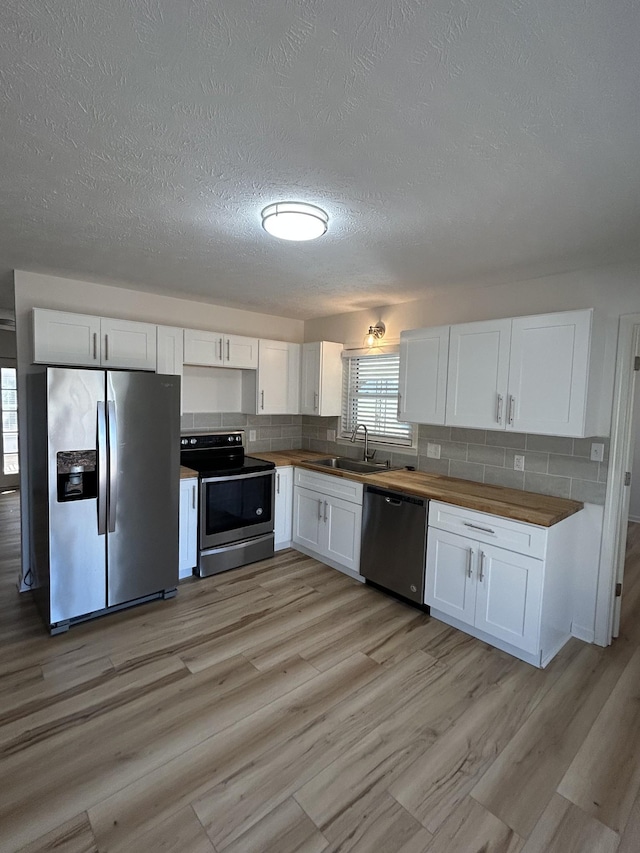 kitchen with tasteful backsplash, stainless steel appliances, sink, and white cabinets