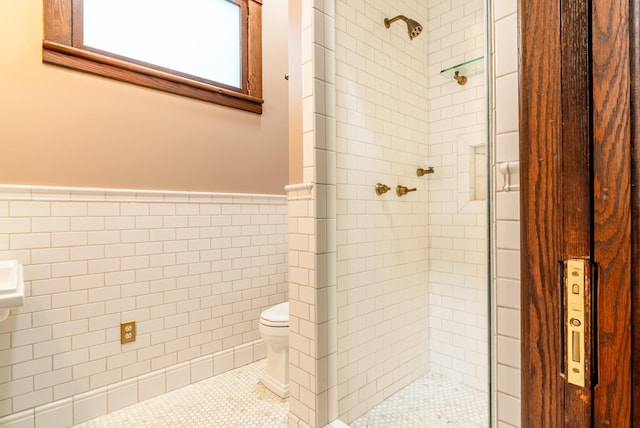 bathroom featuring a tile shower, tile patterned floors, tile walls, and toilet