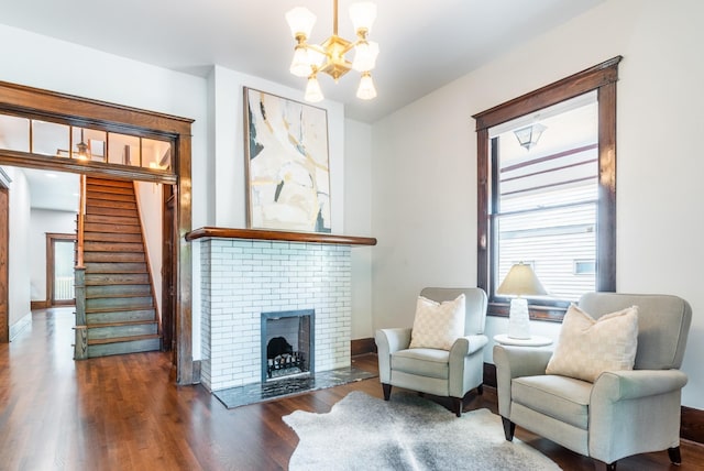 sitting room with dark hardwood / wood-style floors, plenty of natural light, a fireplace, and a chandelier