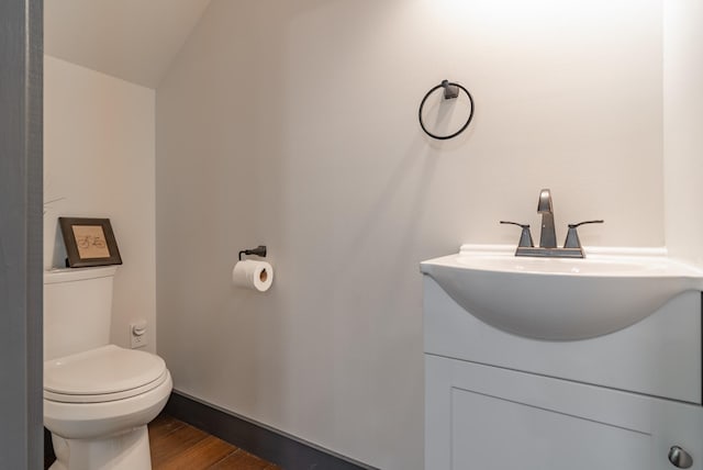 bathroom featuring hardwood / wood-style flooring, lofted ceiling, vanity, and toilet