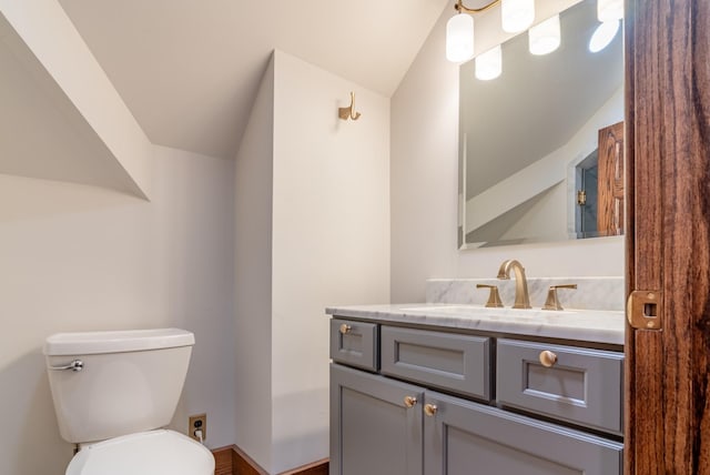 bathroom with lofted ceiling, toilet, and vanity