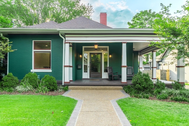 entrance to property featuring a yard and covered porch