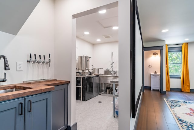 bar with sink, dark hardwood / wood-style floors, and wooden counters