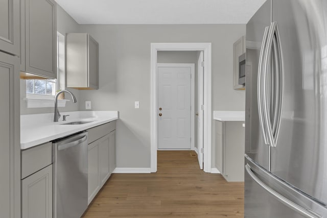 kitchen featuring light hardwood / wood-style floors, stainless steel appliances, gray cabinets, and sink