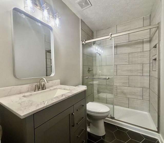 bathroom with tile patterned flooring, vanity, an enclosed shower, a textured ceiling, and toilet