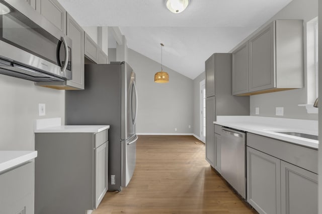 kitchen featuring gray cabinetry, vaulted ceiling, light hardwood / wood-style flooring, hanging light fixtures, and stainless steel appliances