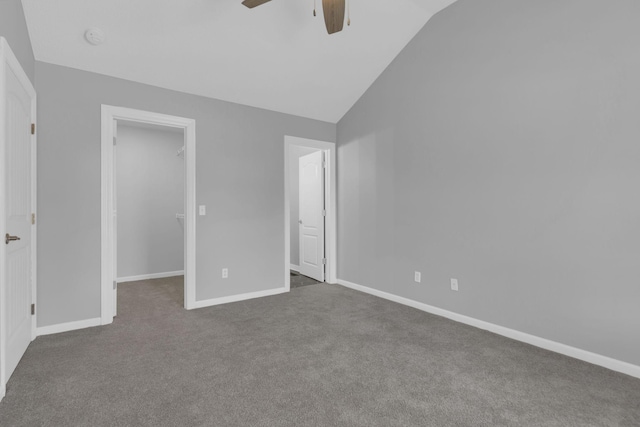 unfurnished bedroom featuring vaulted ceiling, a walk in closet, dark carpet, ceiling fan, and a closet