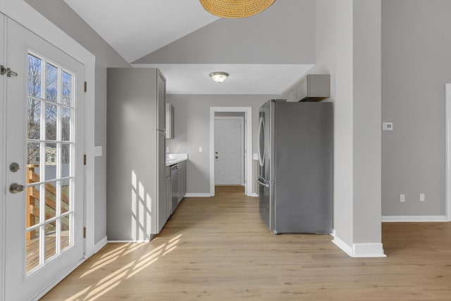 interior space featuring vaulted ceiling, gray cabinetry, stainless steel refrigerator, and light hardwood / wood-style flooring