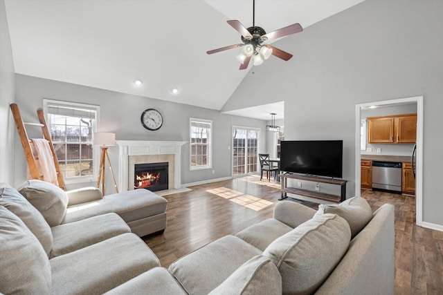 living room featuring a tile fireplace, dark wood-type flooring, ceiling fan, and high vaulted ceiling