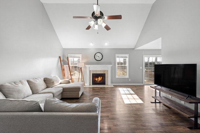 living room with hardwood / wood-style flooring, a tiled fireplace, ceiling fan, and high vaulted ceiling