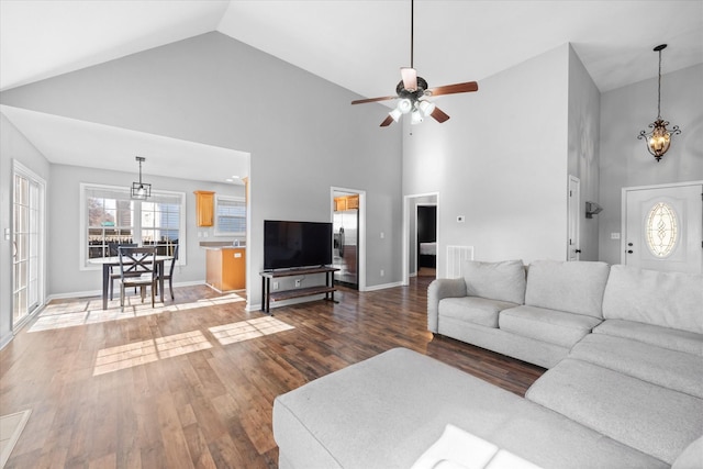 living room featuring ceiling fan with notable chandelier, hardwood / wood-style floors, and high vaulted ceiling