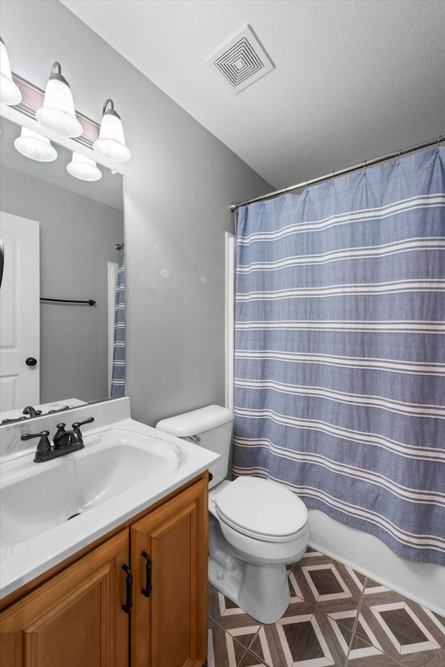 bathroom with vanity, toilet, and a textured ceiling