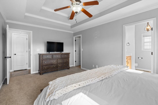 carpeted bedroom featuring ensuite bath, ornamental molding, a raised ceiling, and ceiling fan