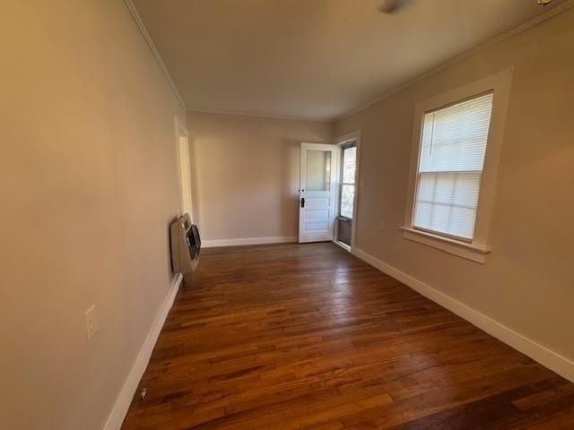 unfurnished room featuring heating unit, dark hardwood / wood-style flooring, and ornamental molding