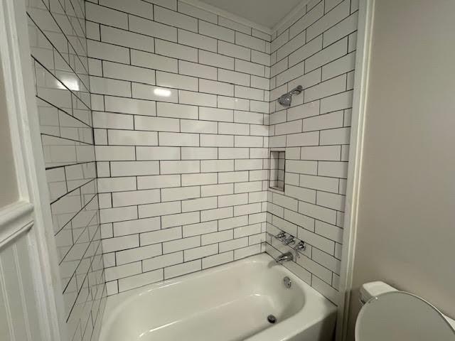 bathroom with tiled shower / bath combo and toilet