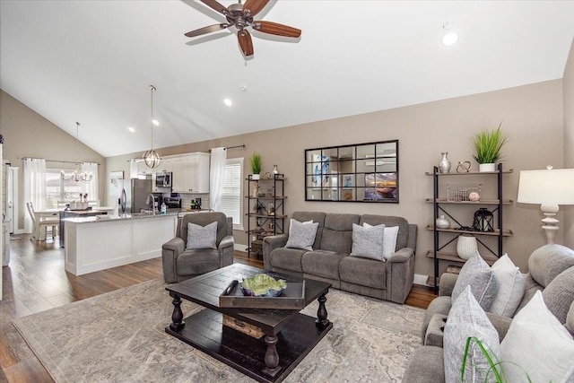 living room featuring hardwood / wood-style flooring, high vaulted ceiling, and ceiling fan with notable chandelier