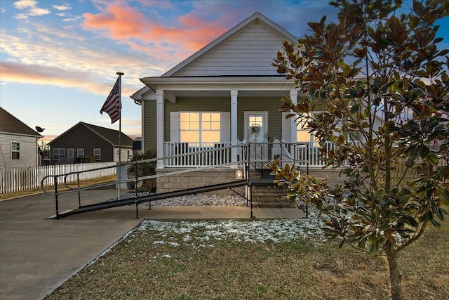 back house at dusk featuring a porch