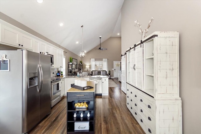 kitchen with stainless steel appliances, a barn door, a kitchen island, and white cabinets