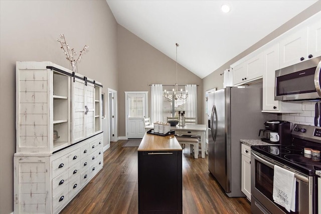 kitchen featuring appliances with stainless steel finishes, white cabinetry, wooden counters, hanging light fixtures, and a center island