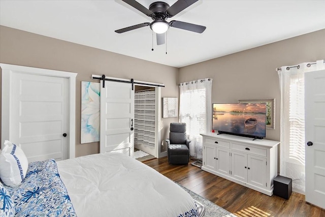 bedroom featuring dark hardwood / wood-style flooring, a barn door, and ceiling fan