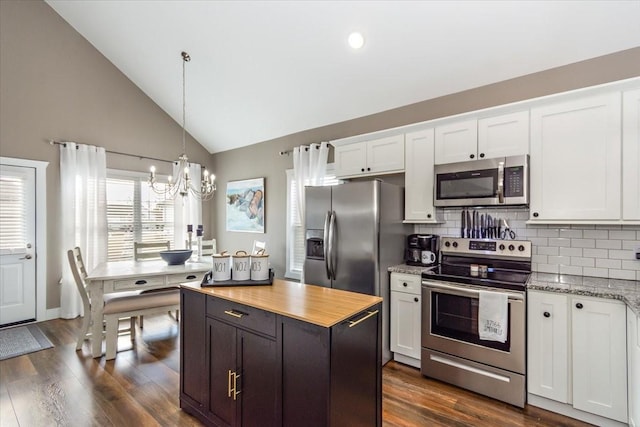 kitchen with backsplash, stainless steel appliances, hanging light fixtures, and white cabinets