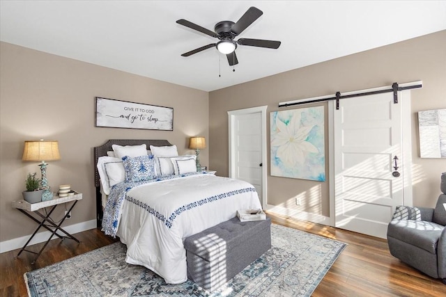 bedroom featuring hardwood / wood-style flooring, ceiling fan, and a barn door