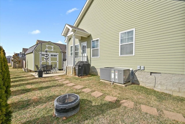 rear view of house featuring central AC, a yard, a shed, and a fire pit