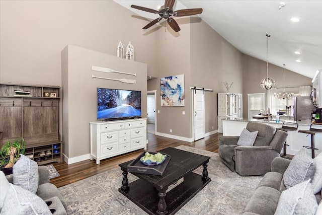 living room with hardwood / wood-style flooring, a barn door, ceiling fan with notable chandelier, and high vaulted ceiling