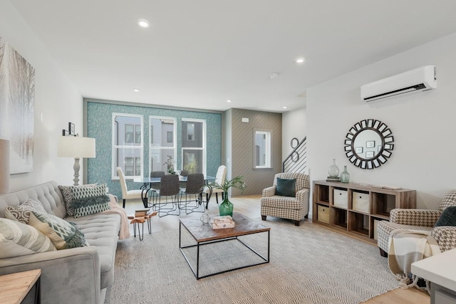 living room with a wall mounted air conditioner and light hardwood / wood-style flooring