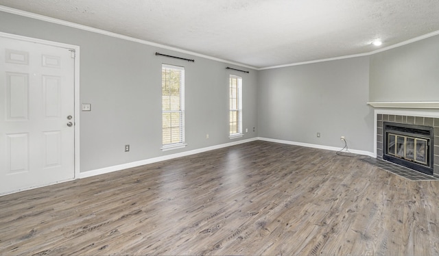 unfurnished living room featuring a tiled fireplace, hardwood / wood-style floors, crown molding, and a textured ceiling