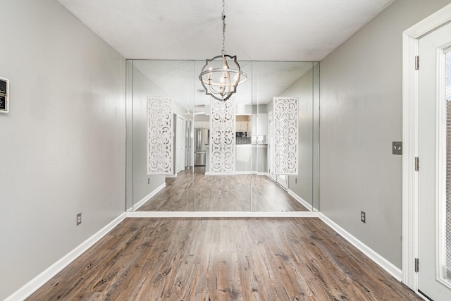 unfurnished dining area with dark wood-type flooring and a chandelier