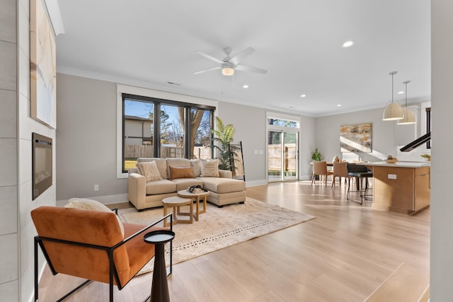 living room featuring light hardwood / wood-style flooring, ornamental molding, and ceiling fan