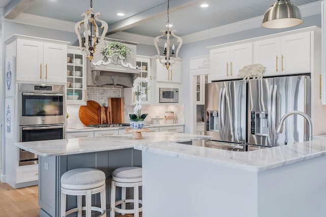 kitchen with appliances with stainless steel finishes, decorative light fixtures, a center island, and white cabinets