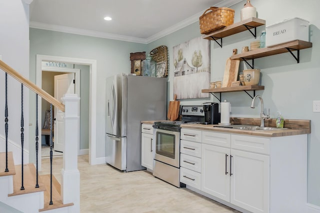 kitchen featuring white cabinetry, appliances with stainless steel finishes, crown molding, and sink