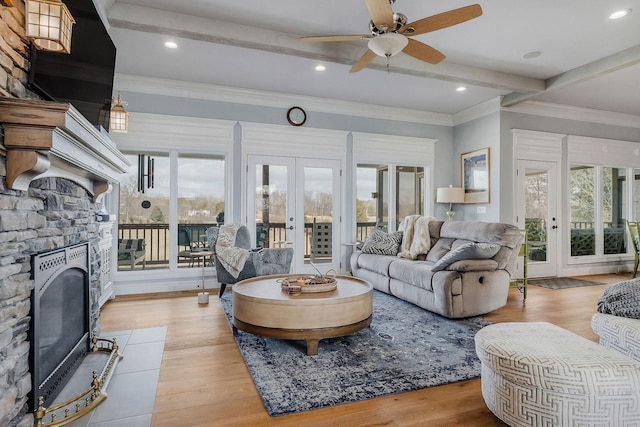 living room featuring beam ceiling, a fireplace, french doors, and light wood-type flooring