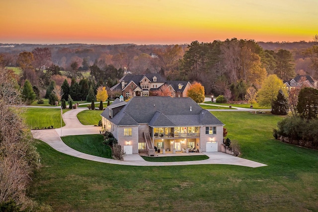 back house at dusk featuring a yard and a garage