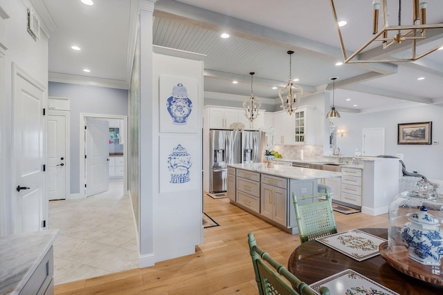 kitchen featuring a kitchen island, decorative light fixtures, white cabinetry, stainless steel refrigerator with ice dispenser, and beam ceiling