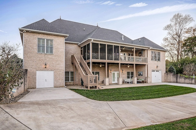 rear view of house featuring a garage, a sunroom, a yard, ceiling fan, and a patio