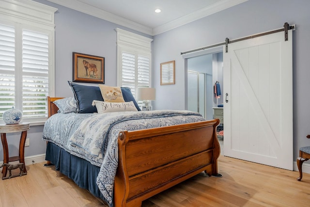 bedroom featuring crown molding, light hardwood / wood-style floors, and a barn door