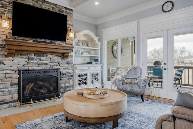 living room featuring french doors, ornamental molding, wood-type flooring, and a fireplace