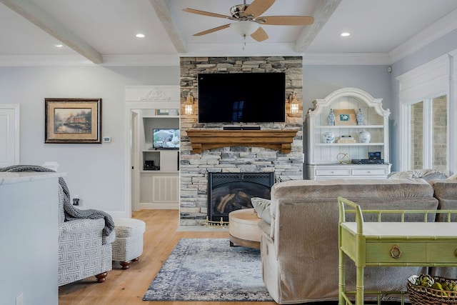 living room featuring crown molding, beam ceiling, light hardwood / wood-style flooring, and a stone fireplace